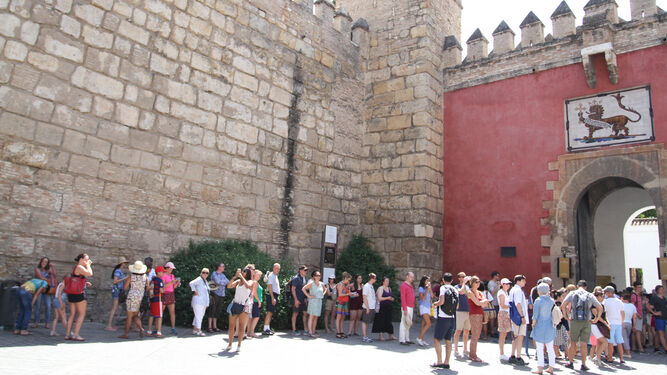 Un grupo de turistas haciendo cola junto a las murallas para acceder al Real Alcázar.