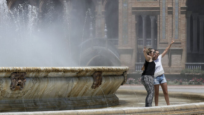 Turistas combatiendo las altas temperaturas en la fuente de la Plaza de España.