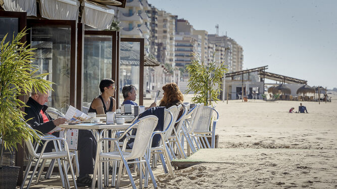 Varios clientes aprovechan un día soleado en la terraza de un chiringuito de la playa de La Victoria.