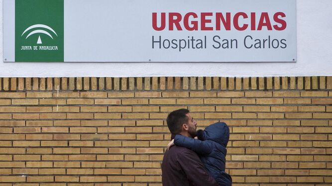 Un hombre con un niño en  brazos llega a las Urgencias del Hospital San Carlos de San Fernando.