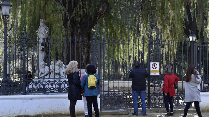 Varios turistas contemplan el monumento a Bécquer tras la verja que lleva varios días cerrada.