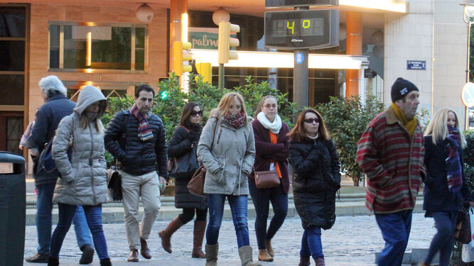 Varias personas abrigadas pasean por Huelva cuando el termómetro marca cuatro grados.
