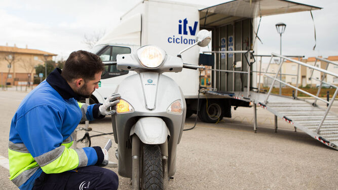 Un trabajador de la ITV inspecciona una motocicleta en la unidad móvil.