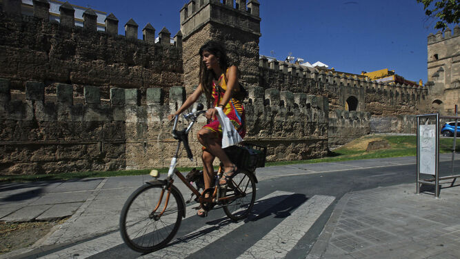Una joven circula por el carril bici junto a la Muralla de la Macarena.