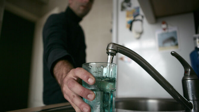 Un hombre llena un vaso de agua en el grifo de la cocina, de archivo.