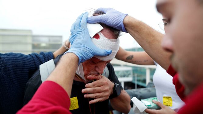 Un sanitario atiende a un manifestante herido tras las cargas de los Mossos contra los miles de independentistas agolpados ante el Aeropuerto del Prat.