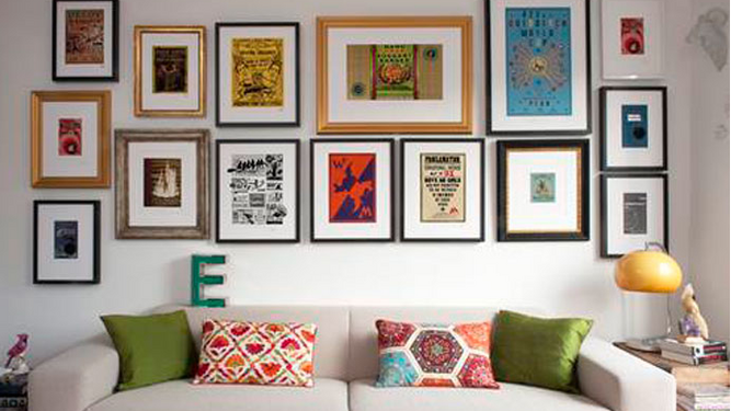 Un salón con la pared del sofá decorada a base de cuadros de diferentes tamaños.