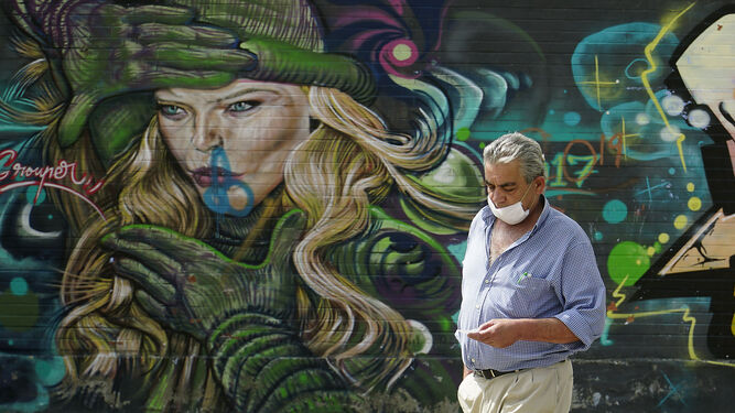 Un viandante camina por un grafiti en Tres Barrios-Amate.