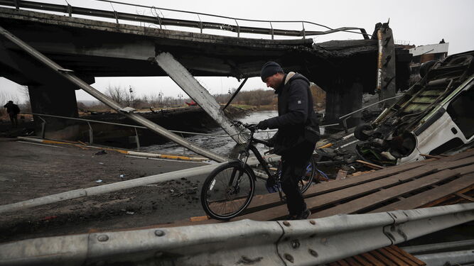 Un lugareño pasa con su bicicleta por un puente destrozado en las afueras de la ciudad de Irpin