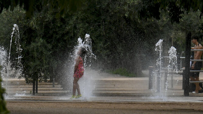 Una niña se refresca en una fuente en Granada.