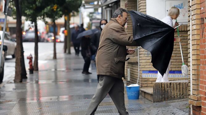 Un hombre recoge su paraguas para entrar en un portal.