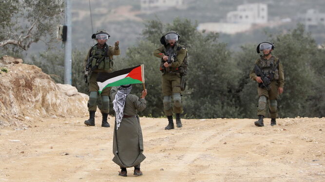 Un soldado israelí apunta a un palestino que porta una bandera junto a la localidad de Beita.