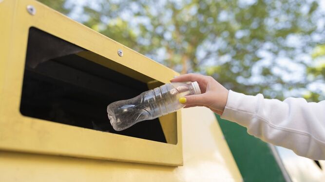 Consumidor reciclando una botella de plástico.