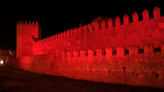 La muralla islámica de Sevilla iluminada de rojo.