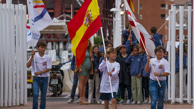 Tres niños llevan las banderas durante la inauguración de la Copa de España Optimist de vela 'Ciudad de Almería'.